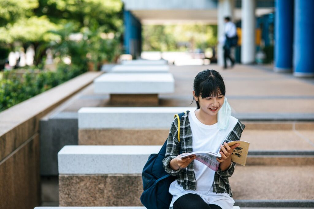 female student sitting stairs read book 1150 24622